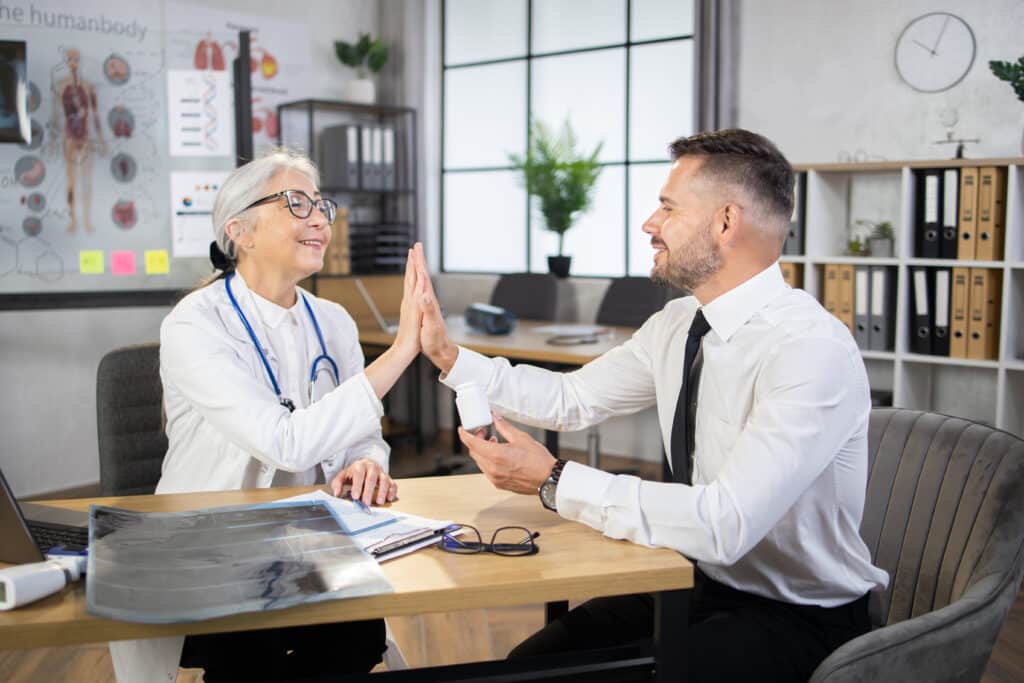 Male patient giving high five to female doctor at cabinet